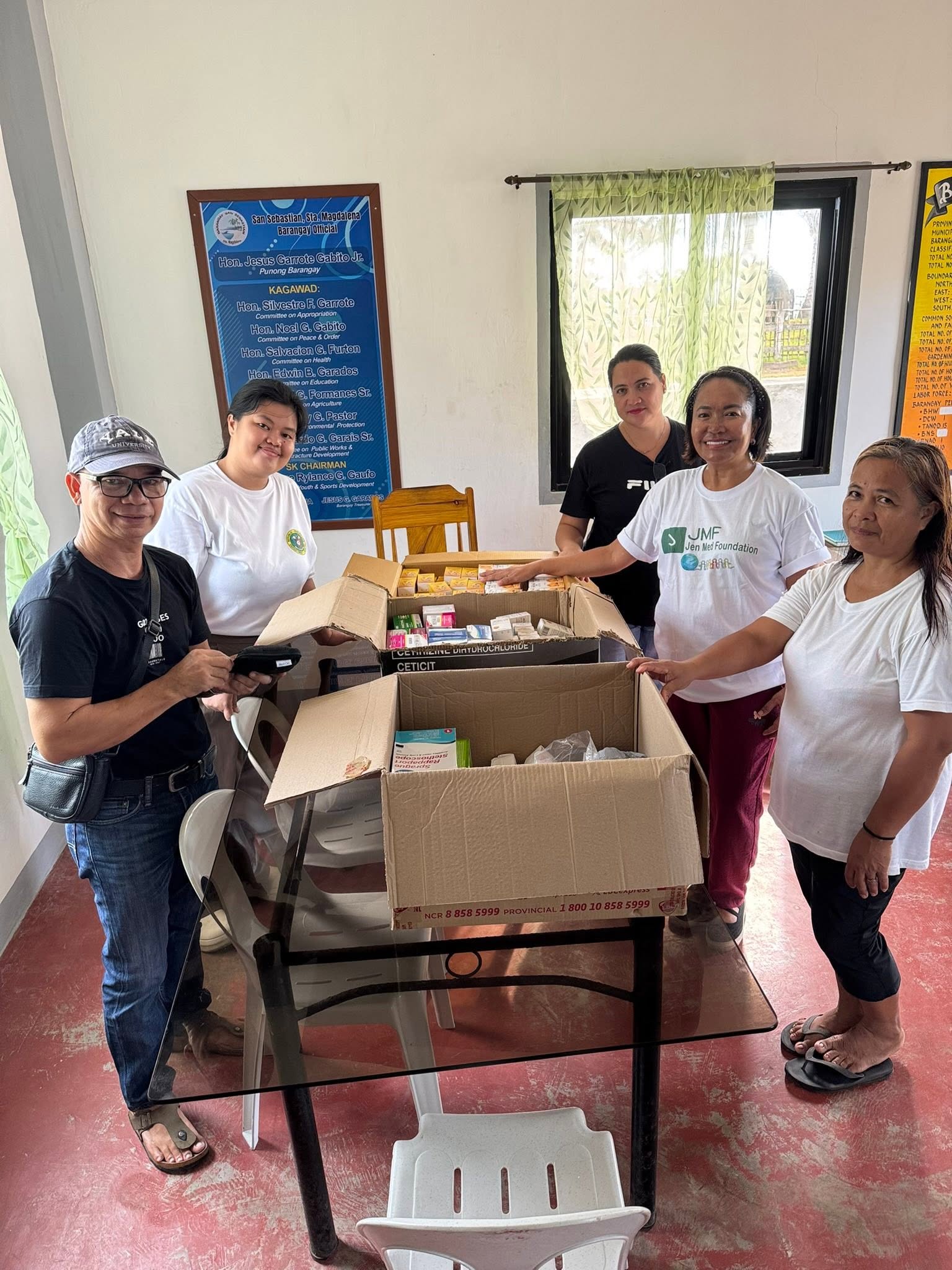 Five people gather around boxes of donated medicines.