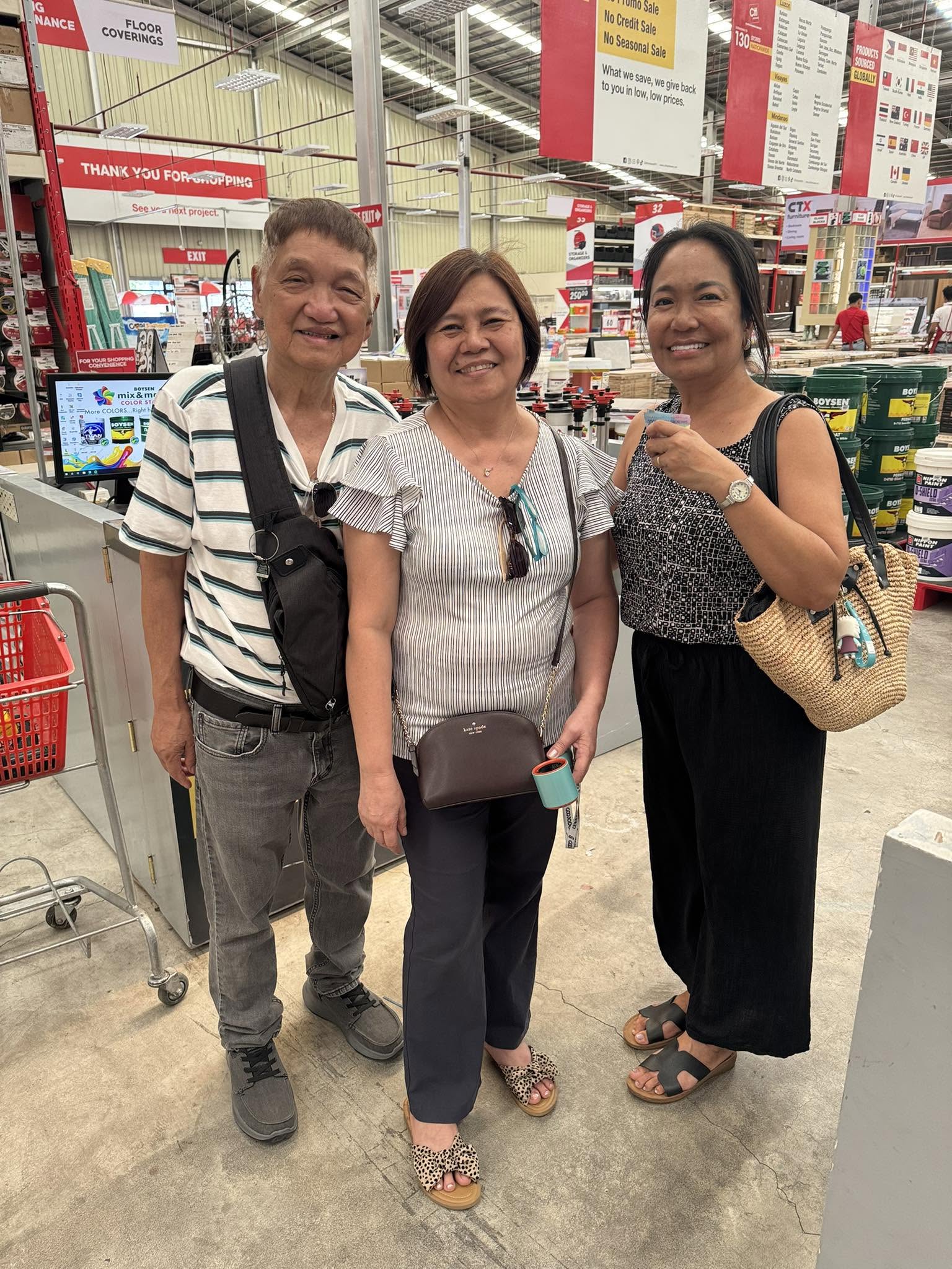 Three smiling people pose together inside a store.